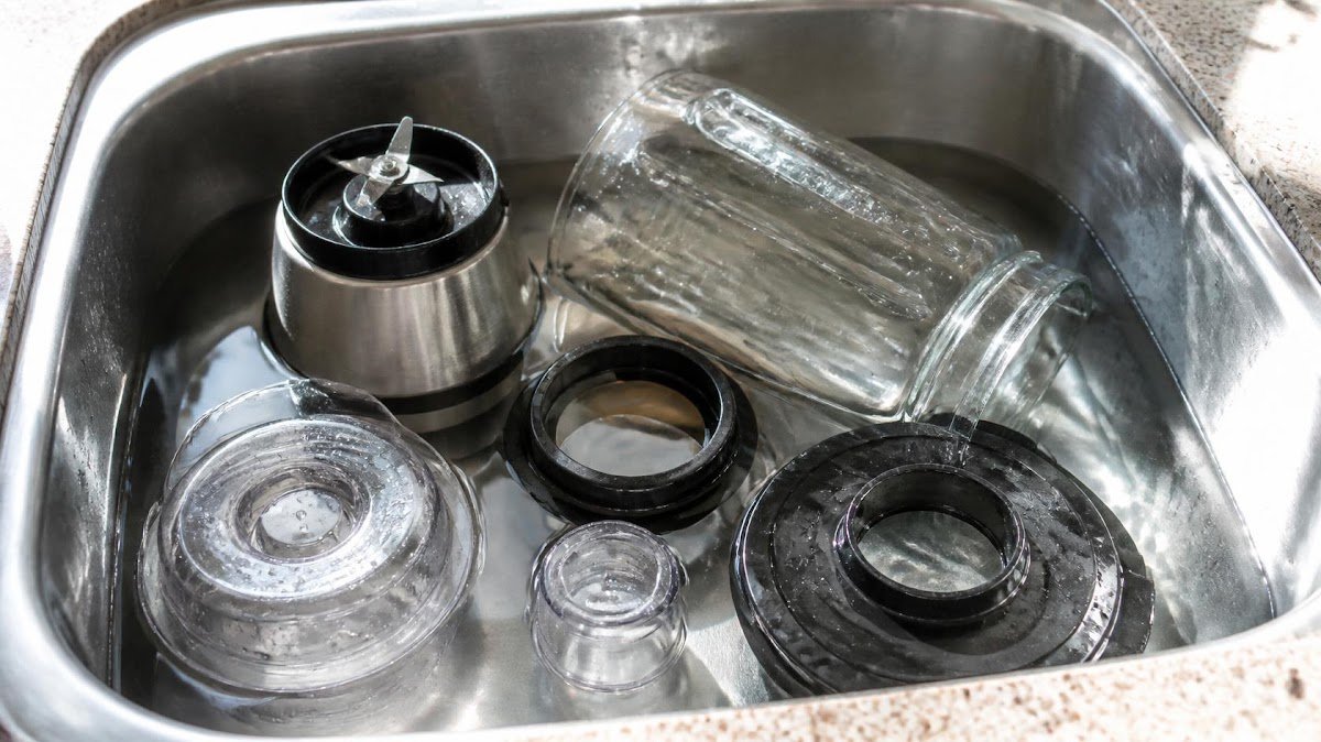 Blender parts being rinsed at sink